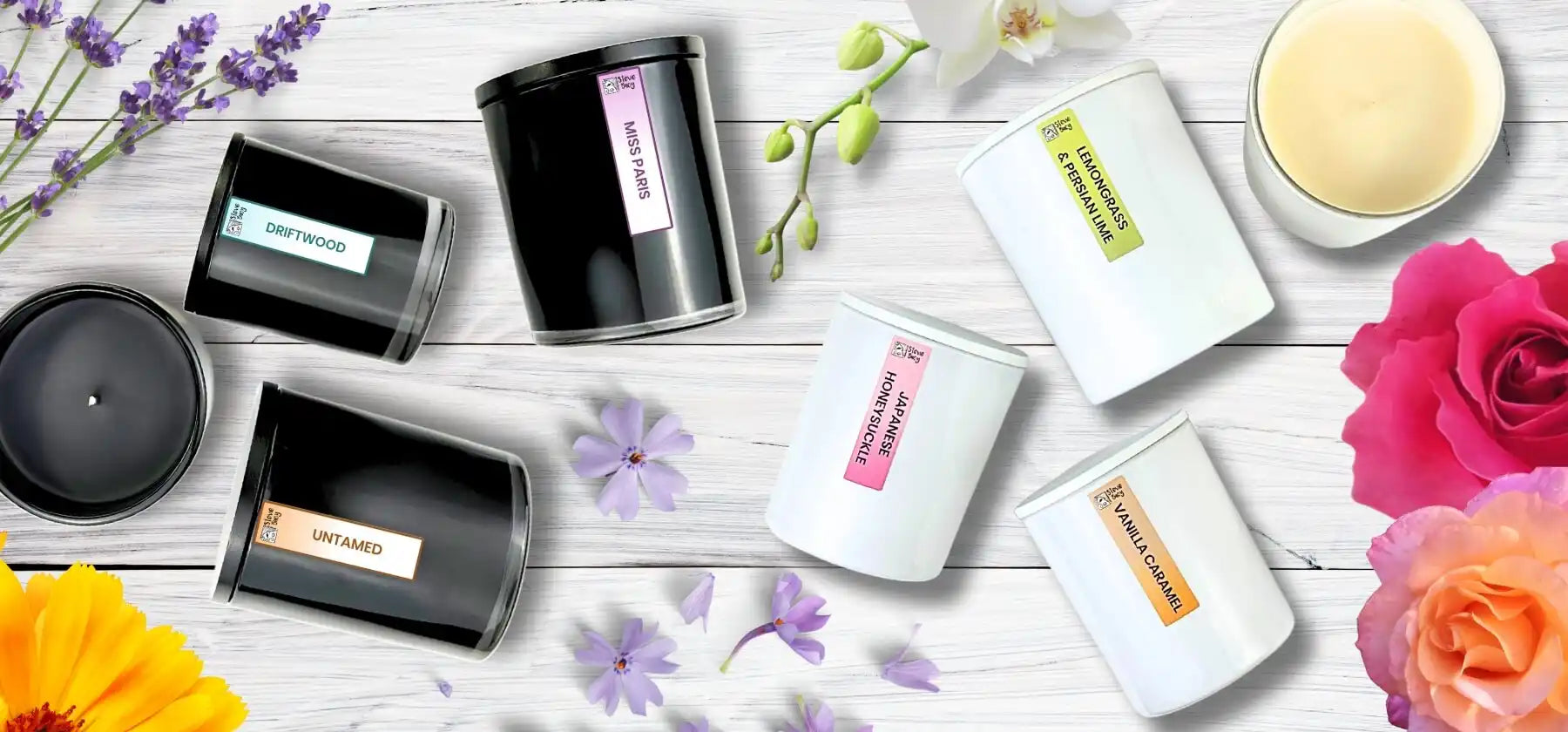 Collection of scented candles in black and white containers with colorful floral accents.