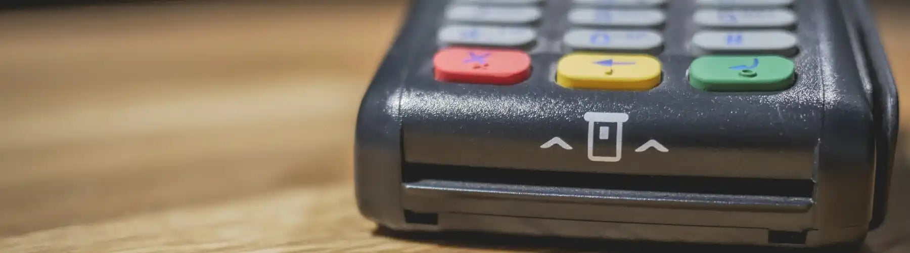 Credit card payment terminal with a keypad showing red, yellow and green buttons.