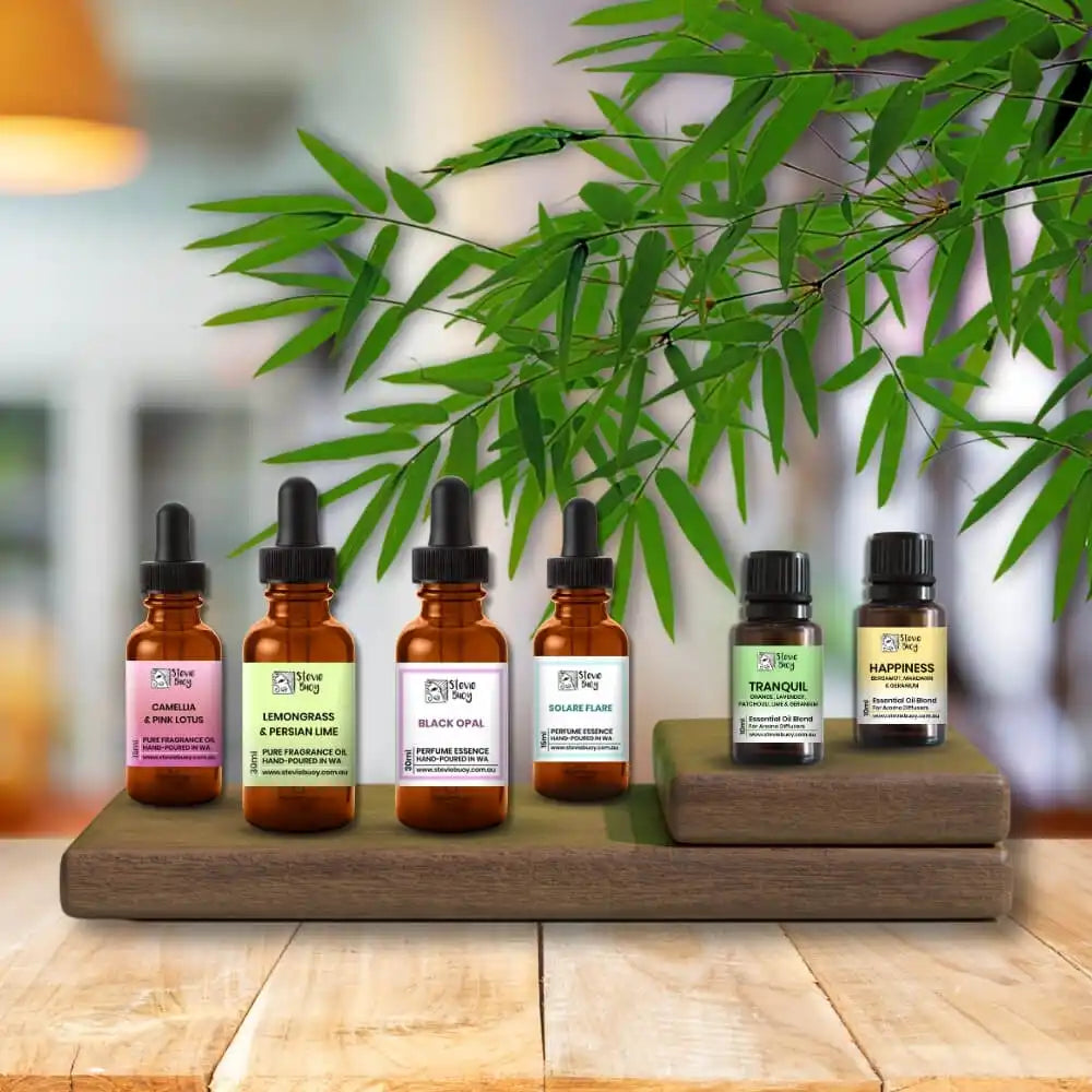 Essential oil bottles arranged on a wooden display stand beneath bamboo leaves.