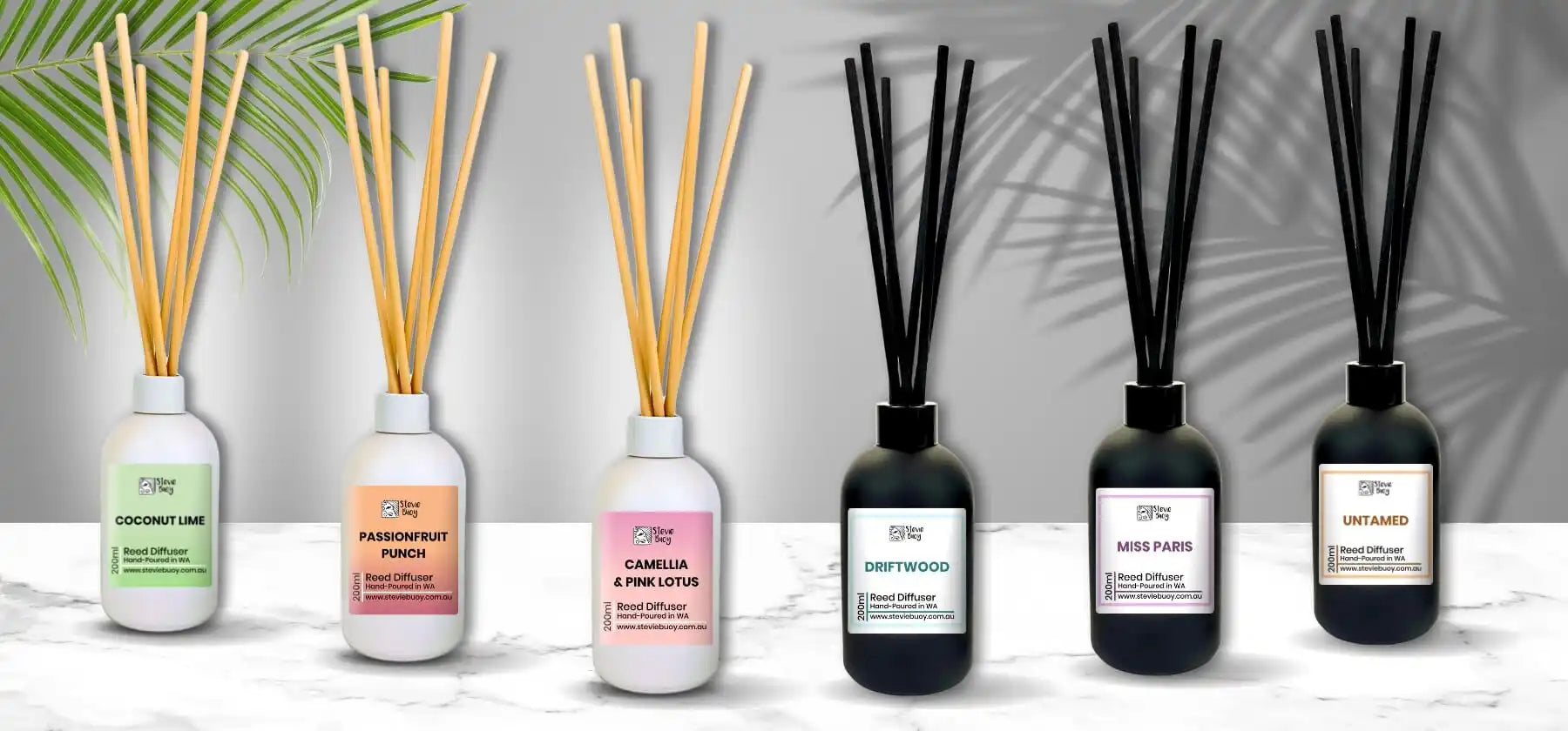 Reed diffusers in clear and black glass bottles with bamboo sticks.